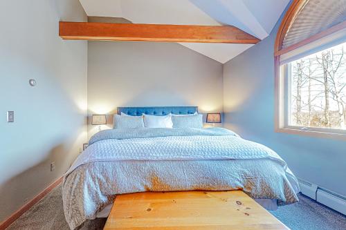 a bedroom with a bed with a blue bedspread and a window at Alpine Abode in Dover