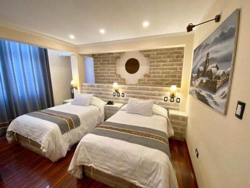 Habitación de hotel con 2 camas y pared de ladrillo en Hotel de Sal Atipax en Uyuni
