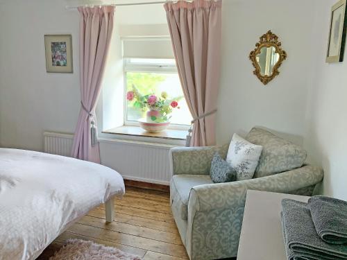a bedroom with a bed and a couch and a window at Golf Cottage in Chinley