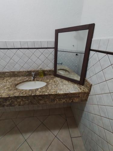 a mirror on a counter with a sink at Hotel Indi Suíte Quádruplo in Ribeirão Preto