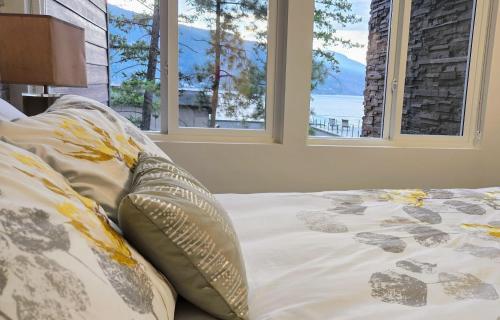 ein Bett in einem Schlafzimmer mit zwei Fenstern in der Unterkunft Lake View Beach, Marina, Pool, HT in Kelowna