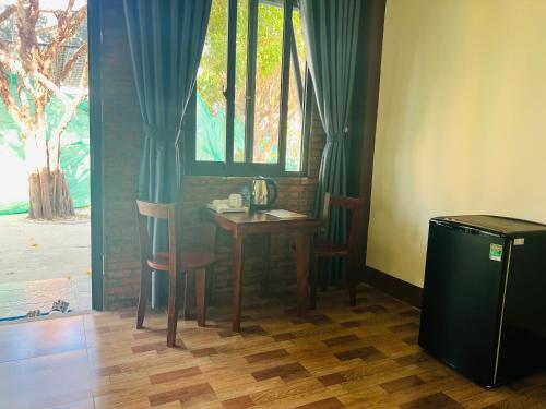 - une table et des chaises dans une chambre avec fenêtre dans l'établissement Tùng Thư garden, à Hà Tiên
