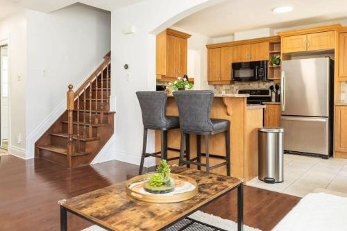 a kitchen with a counter and two bar stools at Modern Cozy 4BR Home with Sunny Patio in Ottawa