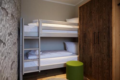 een stapelbed met witte stapelbedden en een groene kruk bij Binnendiek Haus 2 Apartment 8 in Büsum