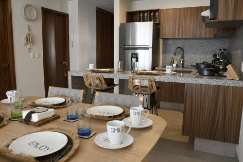 a kitchen with a wooden table with plates and cups on it at Departamento en Bucerías vista al mar in Bucerías