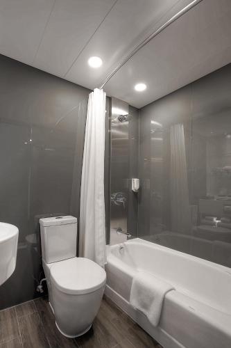 a bathroom with a toilet and a tub and a sink at Stanford Hotel Hong Kong in Hong Kong