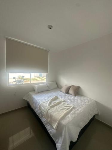 ein weißes Bett in einem Zimmer mit Fenster in der Unterkunft Mónaco in Valledupar