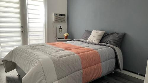 a bedroom with a bed with an orange and gray blanket at •Executive Suite• Quiet, Centrally & Comfortable in Ciudad Juárez
