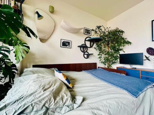 ein Schlafzimmer mit einem Bett und einem Schreibtisch mit einer Pflanze in der Unterkunft Confort au cœur des Puces PARIS Appartement modern in Saint-Ouen