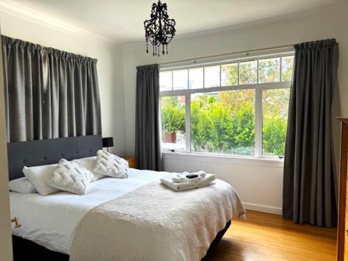 a bedroom with a bed and a large window at Tauranga - Stylish & Centrally Located Near Hospital in Tauranga