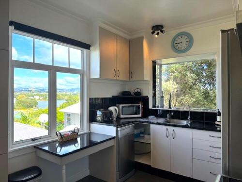 a kitchen with a sink and a clock on the wall at Tauranga - Stylish & Centrally Located Near Hospital in Tauranga