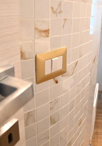 a white tiled bathroom with a light switch at Il Vicoletto sul Mare in Ischia