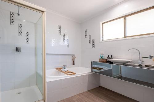 a white bathroom with a tub and a sink at Bicheno Blue Horizon in Bicheno