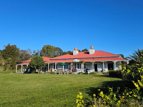 a house with a red roof on a green field at Cape South Estate - International award-winning country estate with Pacific views in Havelock North