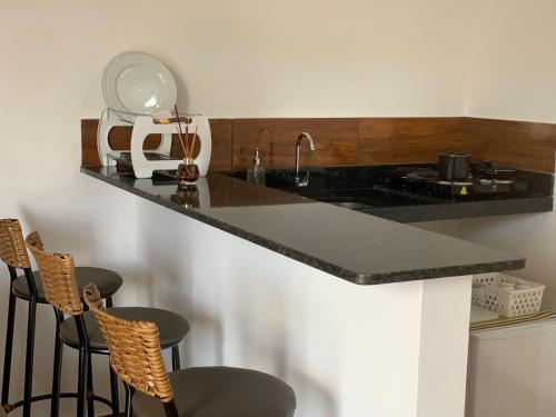a kitchen with a counter with two chairs and a sink at Chalé Aconchego da Serra in Serra de São Bento