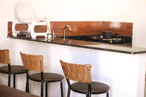 a kitchen with four chairs and a counter with a sink at Chalé Aconchego da Serra in Serra de São Bento