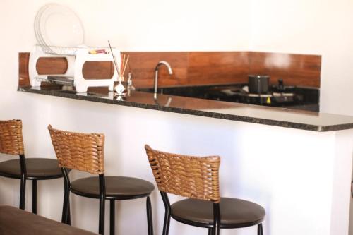 una cocina con 4 sillas y una barra con fregadero en Chalé Aconchego da Serra en Serra de São Bento