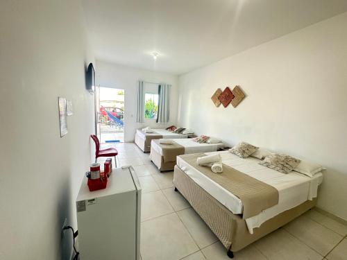 a living room with two beds and a refrigerator at Dellas Pousada in Maragogi