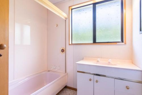 un bagno con vasca, lavandino e finestra di Marina Nest - Timeless & Majestic Kiwi Family Bach - Beautiful Lake Views a Queenstown