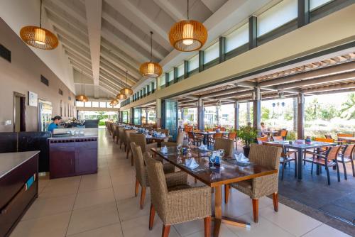 una sala da pranzo con tavoli, sedie e finestre di Diamond Beach Villa Da Nang a Da Nang