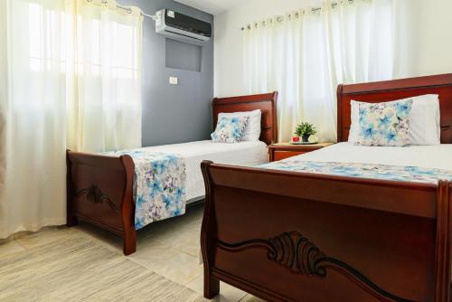 a bedroom with two beds and a tv on the wall at Villa Lugo Lahoz in San Felipe de Puerto Plata