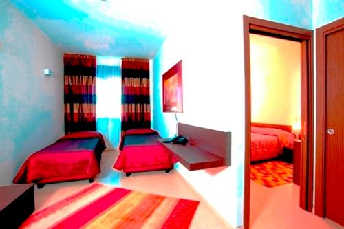a room with two beds and a desk in it at Hotel Massimino in Anguillara Sabazia