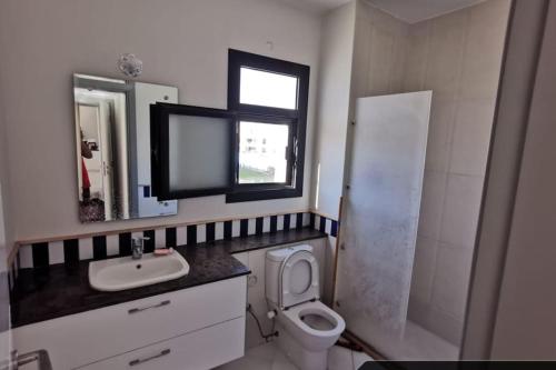 Un baño con inodoro, lavabo y espejo. en Blanca Marassi Chalet on Lagoon, en El Alamein