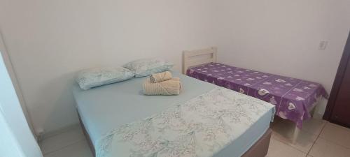 Habitación con 2 camas individuales y sábanas moradas. en Studio Morro das Pedras, en Florianópolis