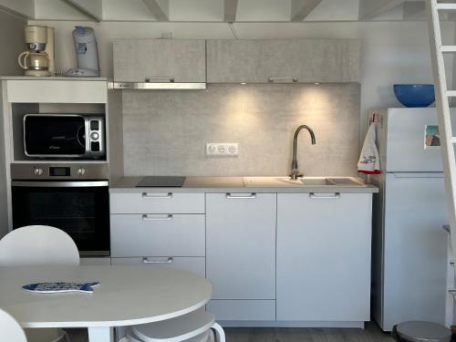 - une cuisine avec des placards blancs, un évier et une table dans l'établissement Appartement lumineux et spacieux à deux pas de la plage de Seignosse - FR-1-239-1042, à Seignosse