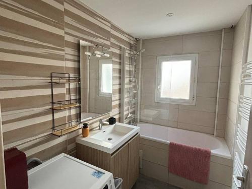 une salle de bain avec un lavabo et une baignoire et un lavabo dans l'établissement Appartement 70 m² en centre-ville, 2 chambres, cuisine équipée, WiFi, non fumeur, animaux non admis. - FR-1-465-111, à Merville-Franceville-Plage