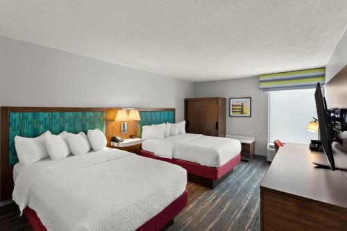 a hotel room with two beds and a desk at Hampton Inn Bridgeport/Clarksburg in Bridgeport