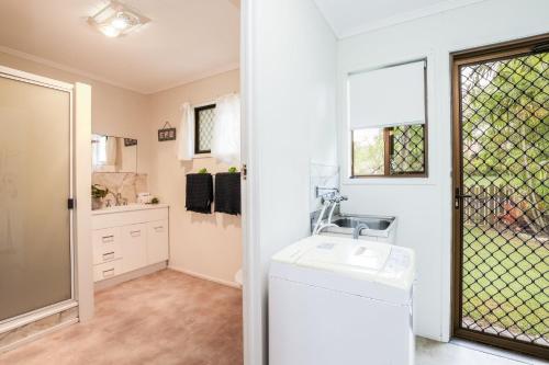 a bathroom with a sink and a washing machine at The Little House - Pet-friendly beach cottage in Agnes Water