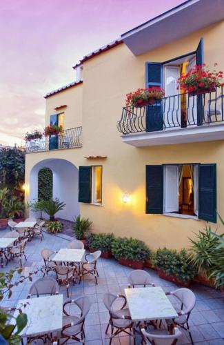 a patio with tables and chairs in front of a building at Hotel Villa Maria Ischia Porto in Ischia