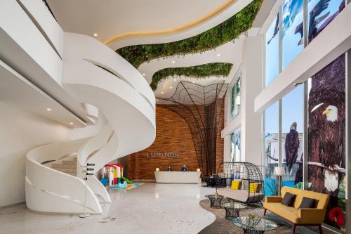 a lobby with a spiral staircase in a building at Luminor Hotel Purwokerto By WH in Purwokerto