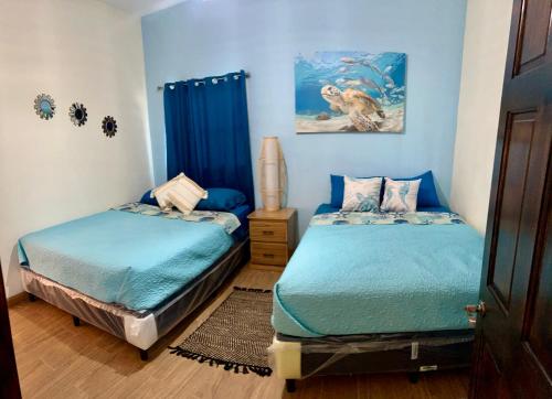 2 Betten in einem Schlafzimmer mit blauen Wänden in der Unterkunft Casa del Sol, Barra de Santiago in Barra de Santiago