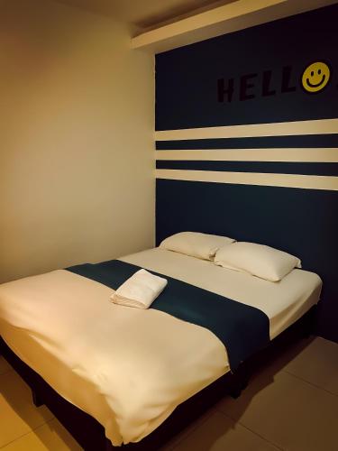 two beds in a room with ahello sign on the wall at V Hotel Sri Gombak in Batu Caves