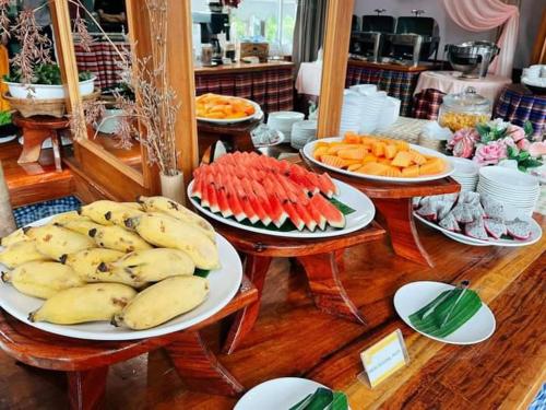 a table topped with plates of fruit and vegetables at Sky View Hotel Buriram in Buriram