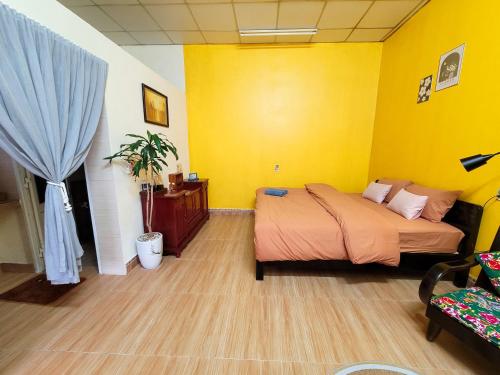 a bedroom with a bed and a yellow wall at Tiny House Cat Ba in Cat Ba