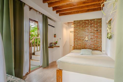 a bedroom with a bed and a brick wall at Ganso & Búho in Ayampe