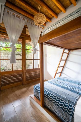 a bedroom with a bed in a room with windows at Ganso & Búho in Ayampe