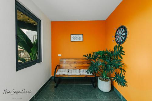 an orange room with a bench and a clock at MiaCasaHanoi - King Bed - Free laundry - Netflix & Rooftop Chill in Hanoi