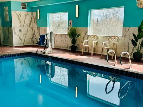 een zwembad met 2 stoelen en een tafel bij Aspen Hotel in Soldotna