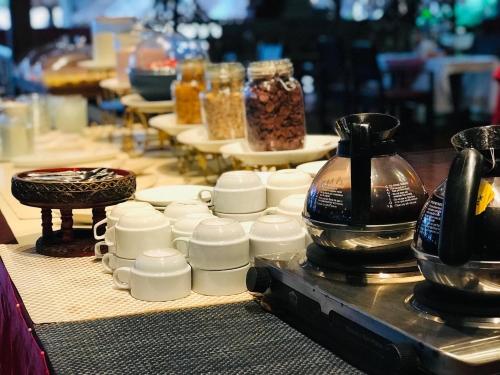a table topped with white cups and jars of food at Sayang Beach Resort Koh Lanta in Ko Lanta