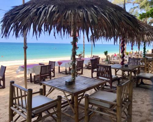 a table with chairs and an umbrella on the beach at Sayang Beach Resort Koh Lanta in Ko Lanta