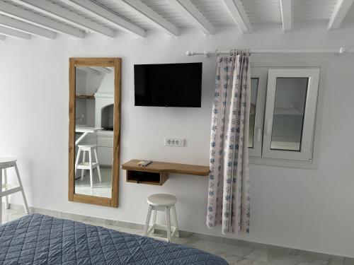 a bedroom with a bed and a mirror and a tv at Anais in Mikonos
