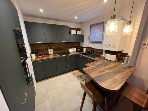 une cuisine avec des placards verts et une table en bois dans l'établissement Maison avec grand jardin proche de Pegasus Bridge, à Ranville