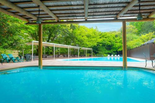 a large swimming pool with a pergola and blue water at Yoshiike Ryokan in Hakone