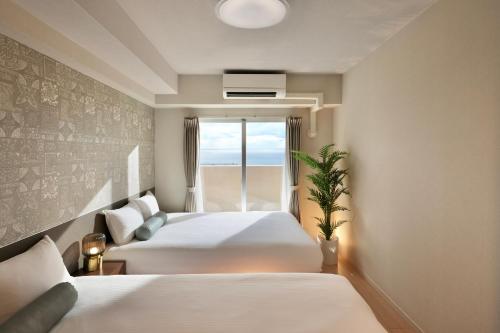 宮古島にあるシティライフ宮古ラブ二ールのベッド2台と窓が備わるホテルルームです。