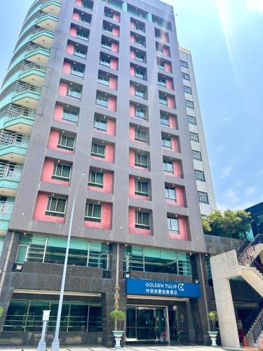 a tall building with red windows in front of it at Golden Tulip Zhong Xin Hotel Taichung in Taichung