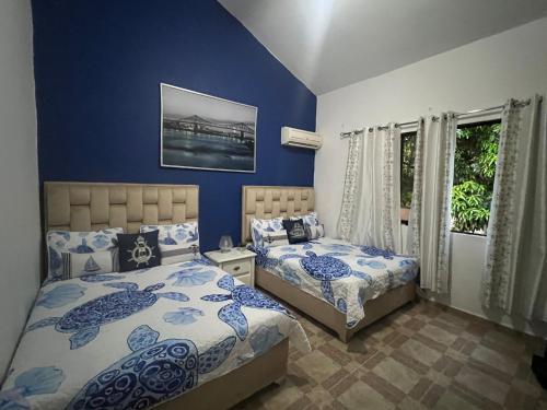 2 camas en un dormitorio con paredes azules en Casa privada 4 habitaciones aires, piscina billar agua caliente 3 minutos de la playa en Río San Juan